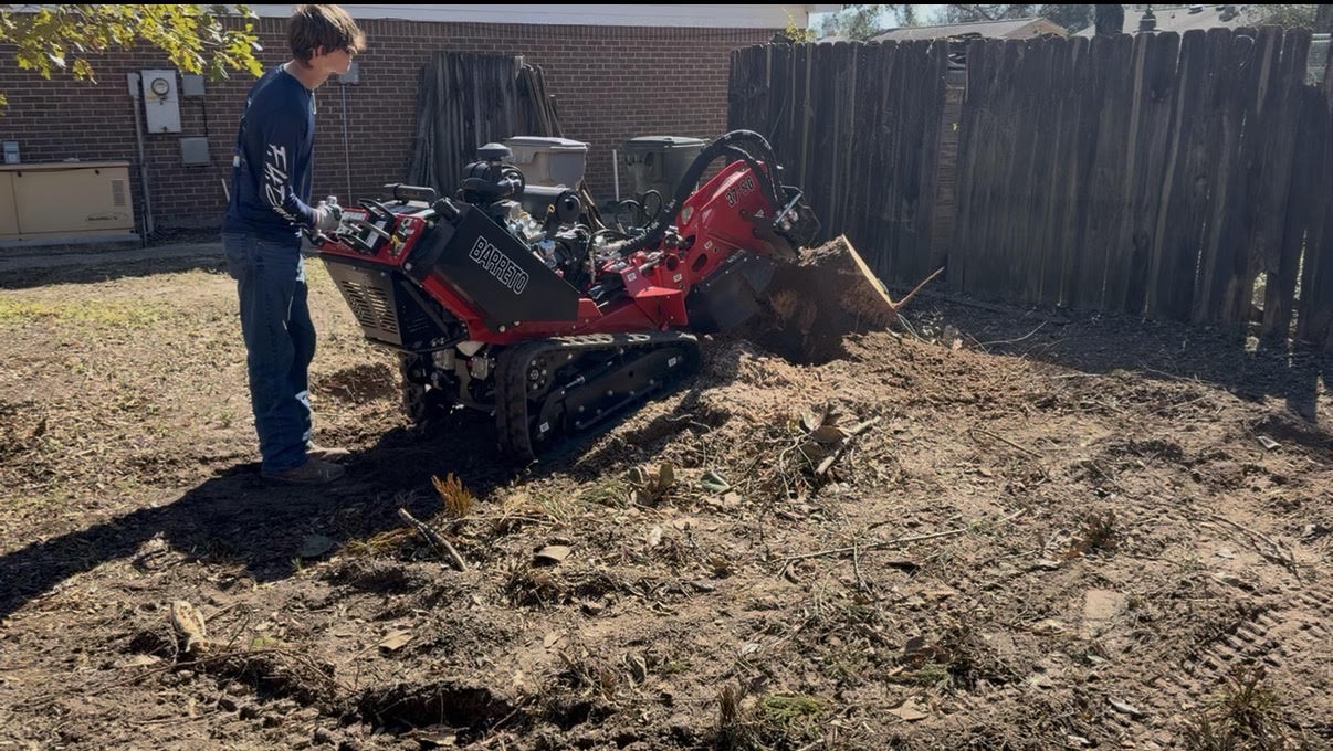 Stump grinder cutting a stump beside a fence